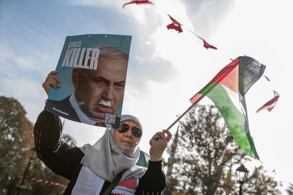 A woman in Turkey holds a sign comparing Netanyahu to Hitler.